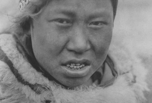 A Hooper Bay Askinarmiut boy poses wearing a circular cap (uivqurraq) and fur parka, photograph by Edward S Curtis (1930).
