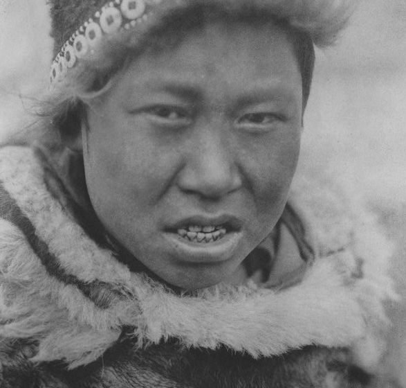 A Hooper Bay Askinarmiut boy poses wearing a circular cap (uivqurraq) and fur parka, photograph by Edward S Curtis (1930).